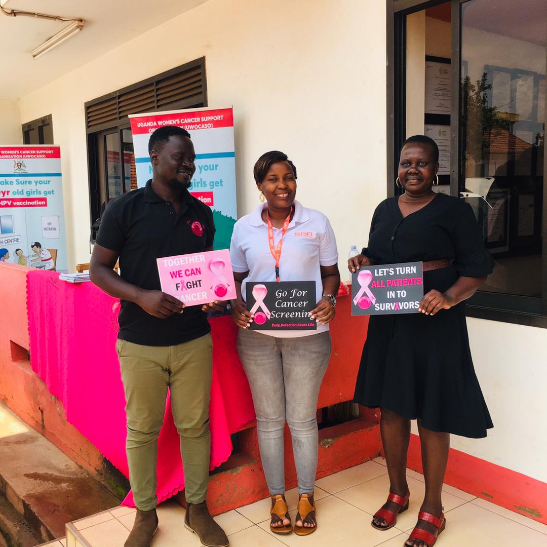 Three individuals holding placards against cancer