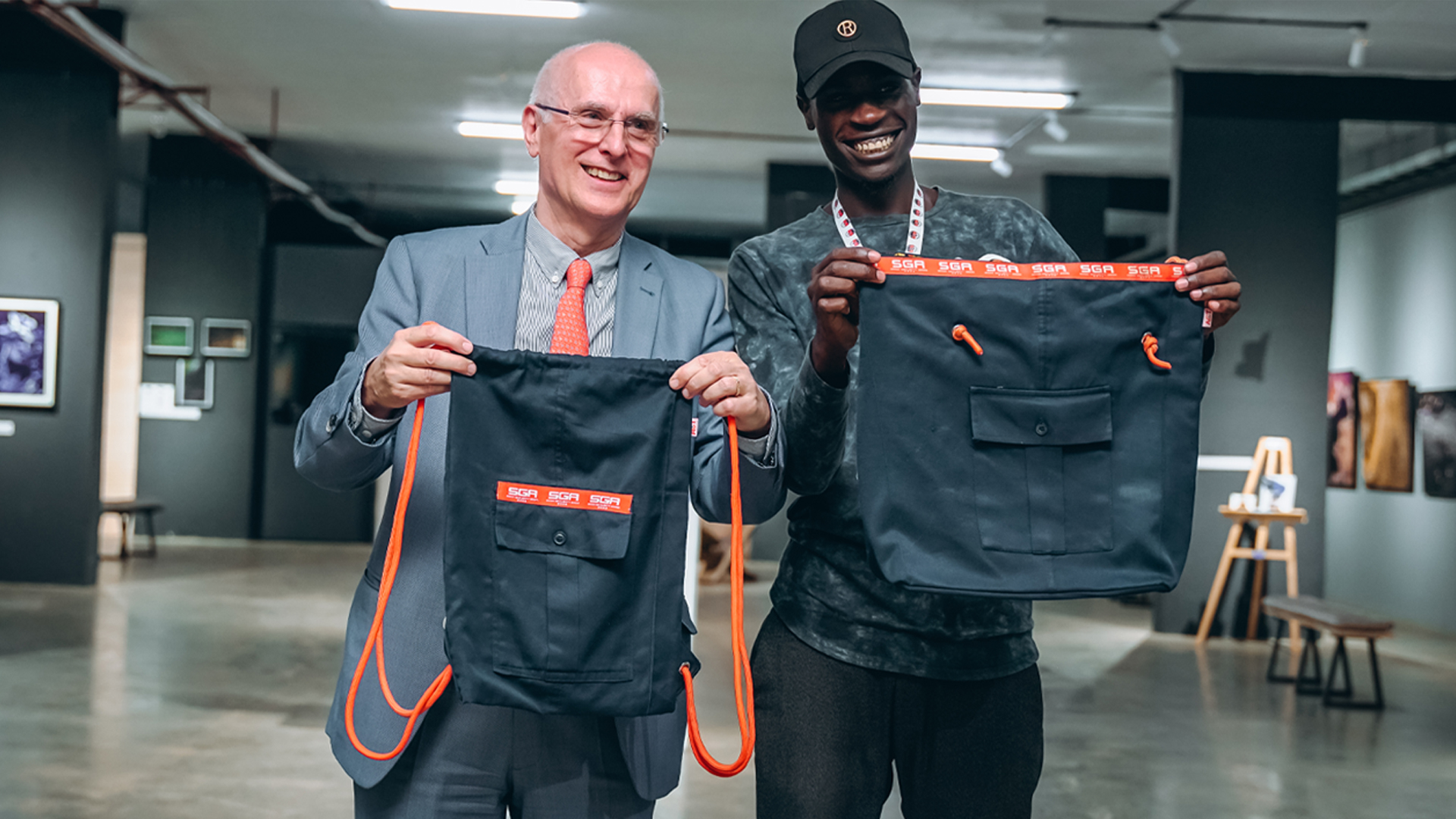 Two men posing while holding school bags